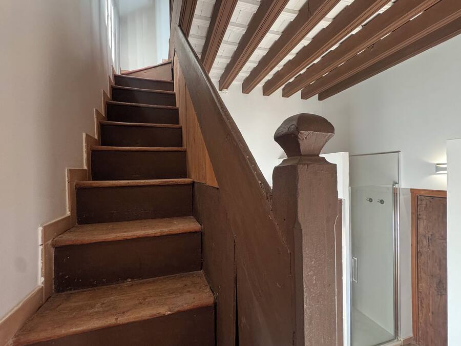 Una escalera de madera con un vidrio en la parte superior que da a una habitación.