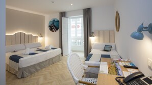 Habitación de hotel con dos camas, un escritorio con una computadora portátil, una silla y vista al mar a través de una ventana.