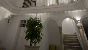 Un atrio de varios niveles con un tragaluz central, barandillas blancas y una escalera.