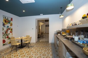 A dining area with a patterned floor, a wall with floral wallpaper, and a buffet counter with various food items. - Casual Con Duende Cádiz Hotel by Casual Hoteles (Cádiz)