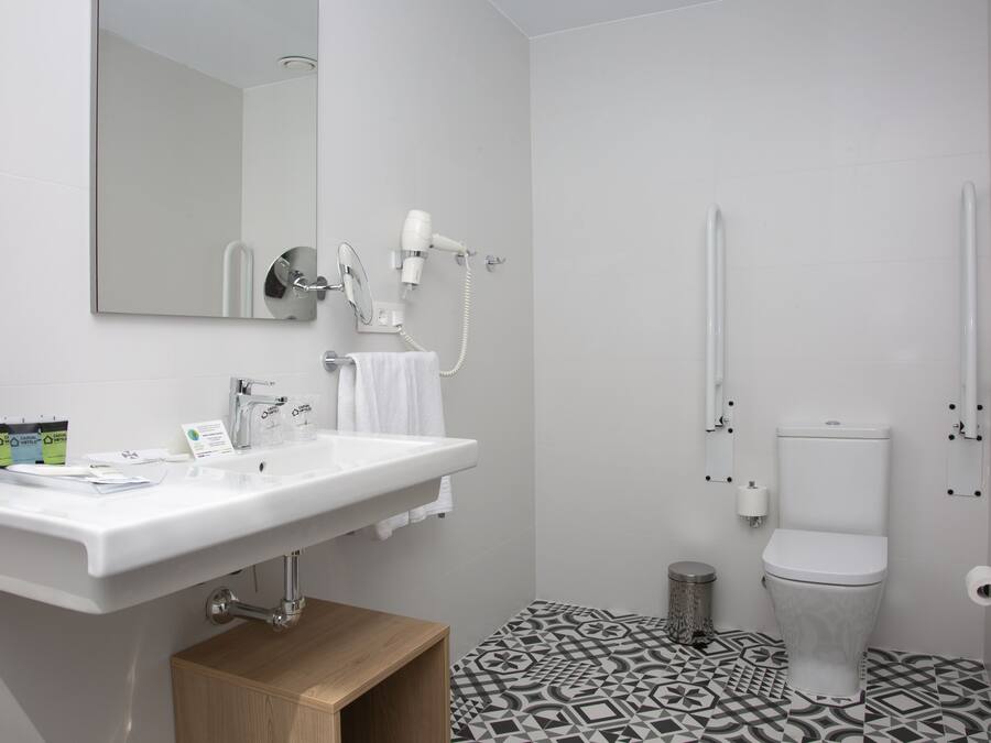 Un baño moderno con lavamanos, espejo y retrete blancos.