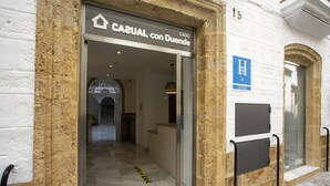 Entrada de hotel con un cartel que dice "CASUAL con Dueño" y un felpudo con la inscripción "HOTEL CASUAL".