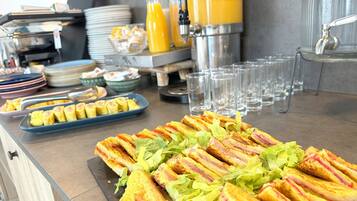 Ein reich gedeckter Buffetstisch mit Sandwiches, Tellern und Gläsern.