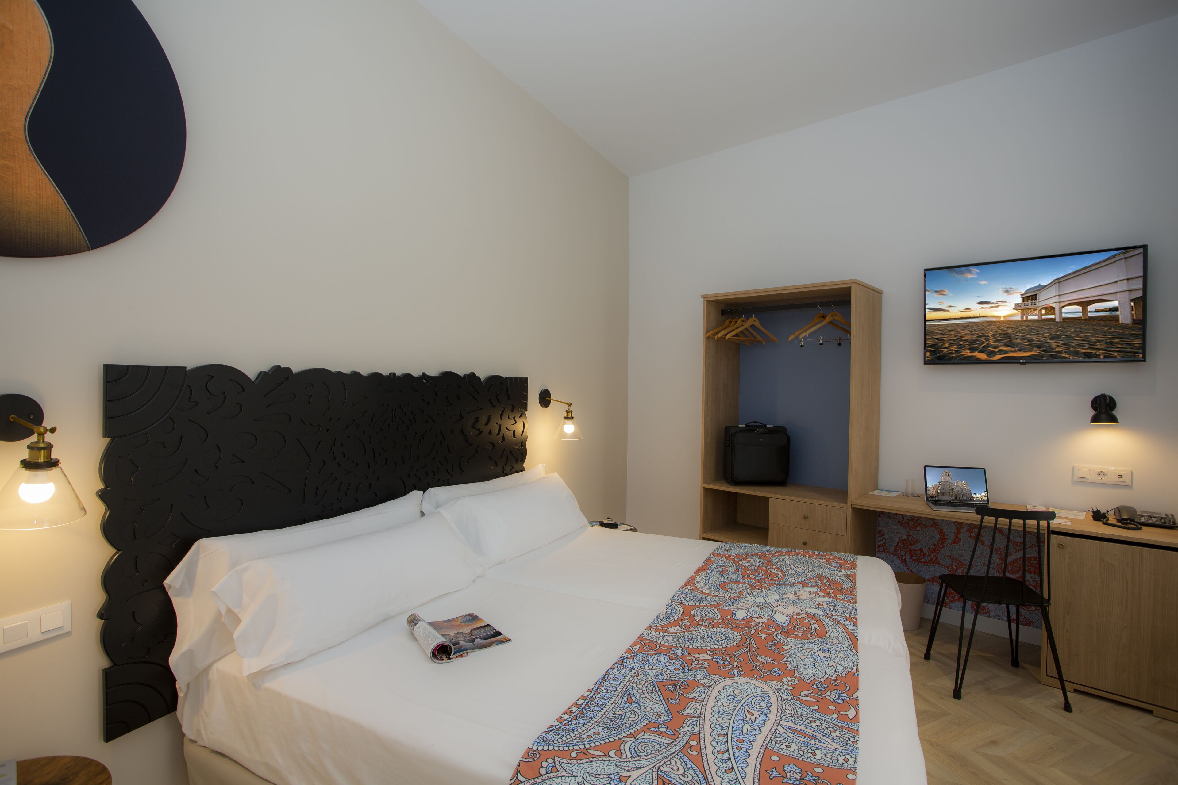 Una habitació d'hotel amb un llit gran, un escriptori amb un ordinador portàtil, una cadira i un armari.