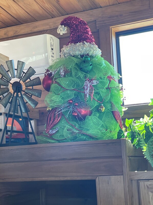 A rustic wooden interior with a decorative windmill and a Christmas tree adorned with green foliage and ornaments. - A&M Country Living little sunset (College Station)