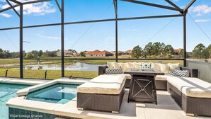 A covered outdoor seating area with a pool, wicker furniture, and a view of a residential area. - Spacious Pool Area With Lake View - 5bd/4.5ba Pool Home #5av139 (Davenport)