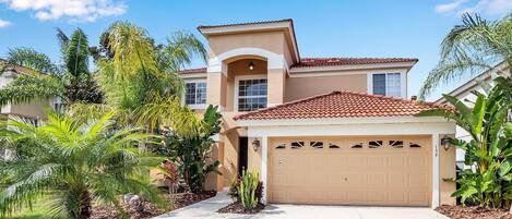 A two-story house with a beige facade, a red-tiled roof, and a garage.