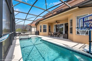 A swimming pool with a covered patio area, a basketball hoop, and outdoor furniture. - Spacious Pool Area With Lake View - 5bd/4.5ba Pool Home #5av139 (Davenport)