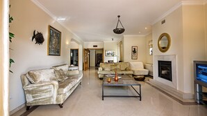 A spacious living room with a fireplace, two sofas, a coffee table, and a television. - Villa Luz - Stunning 4-Bed Villa (Vilamoura)