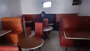 A restaurant interior with red seating, a small TV on the wall, and a tiled floor. - Silver Spoon Motel (Kerugoya)