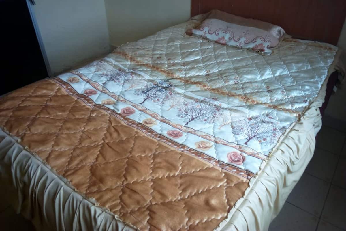 A bed with a quilted cover and a brown quilted throw.