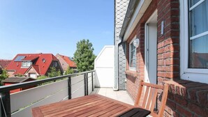 Un balcon avec une table et une chaise en bois, un mur en briques et une fenêtre.