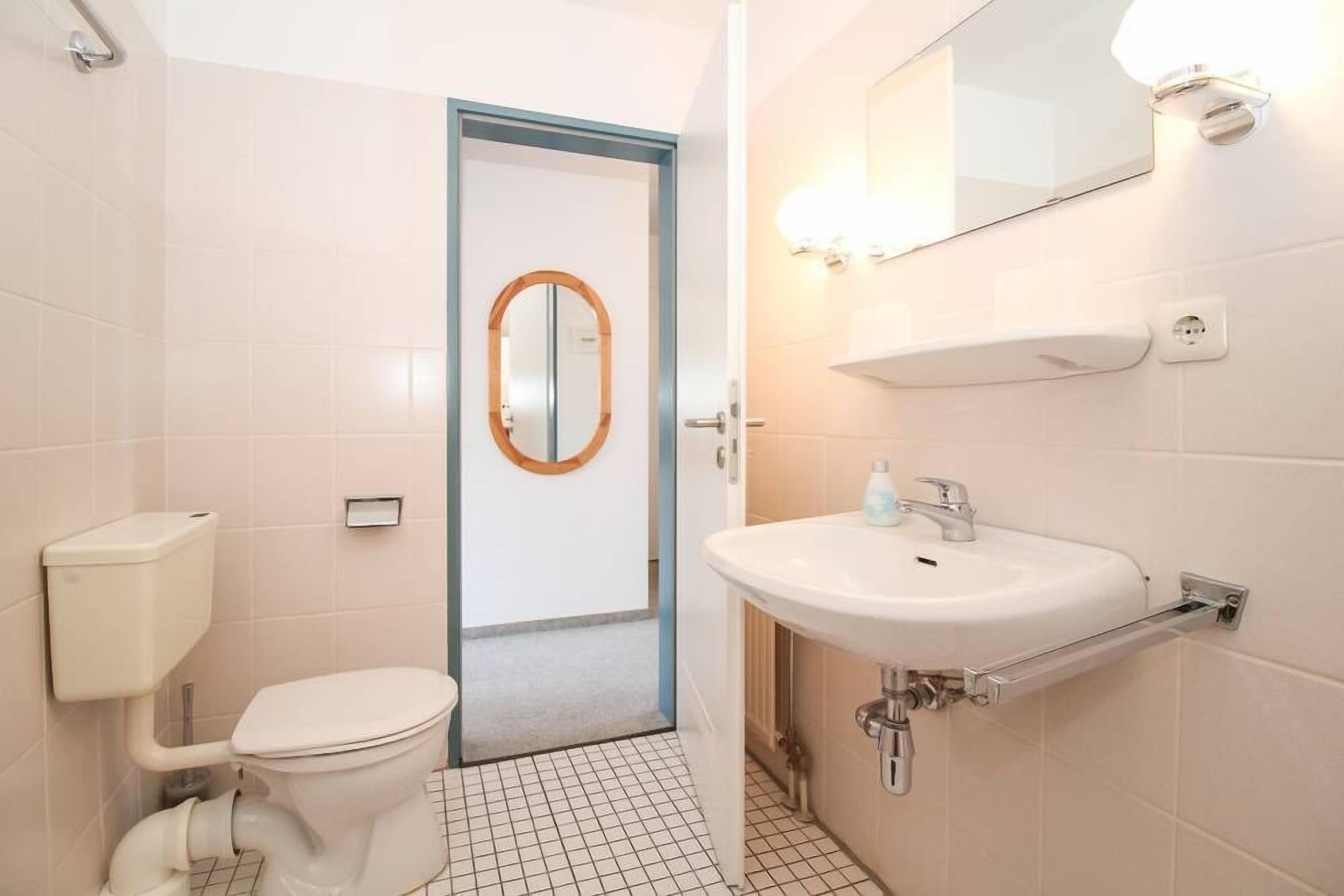 A bathroom with a toilet, sink, and mirror.