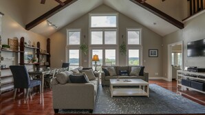 Un salón amplio con techo alto, ventanas grandes y una zona de estar acogedora.