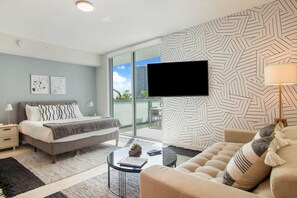 A modern bedroom with a bed, a sofa, a TV, and a balcony with a view. - Large Studio W/Oversized Balcony & Bay Views! (Miami)