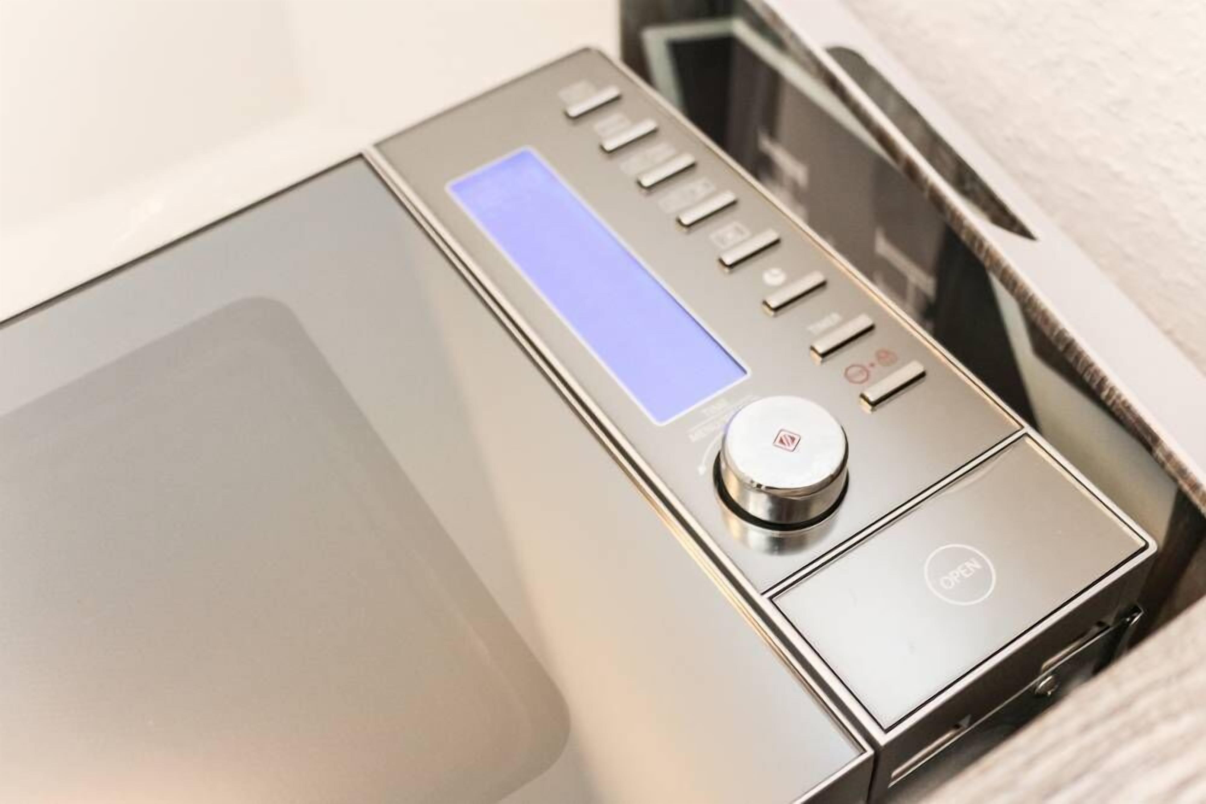 A modern, metallic device with a digital display and control buttons, likely a piece of equipment in a room.