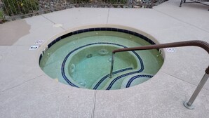 Ein Whirlpool mit gefliestem Rand und einer Metallleiter.