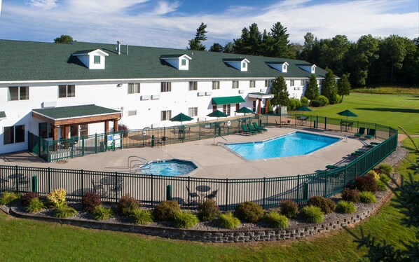 A large hotel with a swimming pool, outdoor seating, and a well-maintained lawn. - Manistee National Golf and Resort (Manistee)