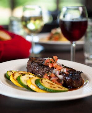 A plate of steak with grilled vegetables and a glass of red wine. - Manistee National Golf and Resort (Manistee)