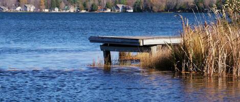 A wooden dock extending into a calm lake with houses in the background.