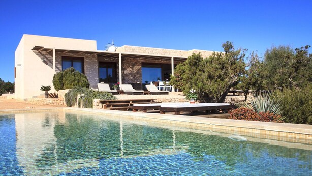 A modern building with a pool, outdoor seating, and a stone facade.
