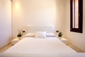 A large bed with a white headboard and two bedside tables, each with a plant. - Romero en Can Corda, Chalet 4 Dormitorios 4 Baños con piscina en Cap de Barbaria Formentera (Sant Francesc de Formentera)