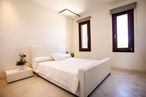 A bedroom with a bed, bedside tables, and a window.