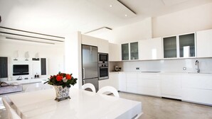 A modern kitchen with white cabinetry, a built-in oven, and a stainless steel refrigerator.