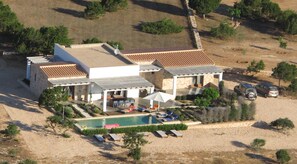 Enjoy panoramic views from this villa's hillside patio, featuring a pool and lounge chairs.