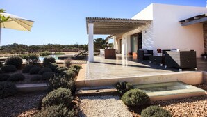A modern outdoor patio with a pool, seating area, and a covered walkway. - Santolina en Can Corda, Chalet 4 Dormitorios 3 Baños con piscina en Cap de Barbaria Formentera (Sant Francesc de Formentera)