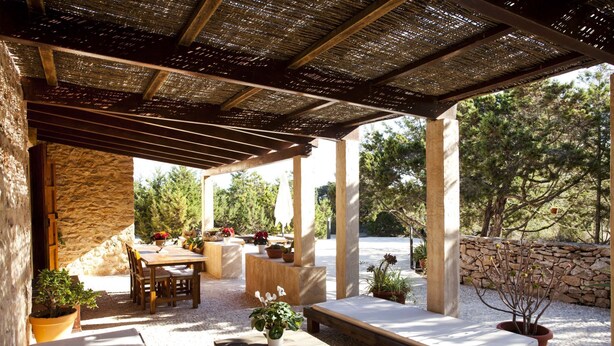Une terrasse extérieure avec des murs en pierre, des meubles en bois et des plantes en pot.