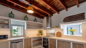 Una cucina moderna con travi in legno, scaffali a incasso, una finestra e una lavastoviglie.