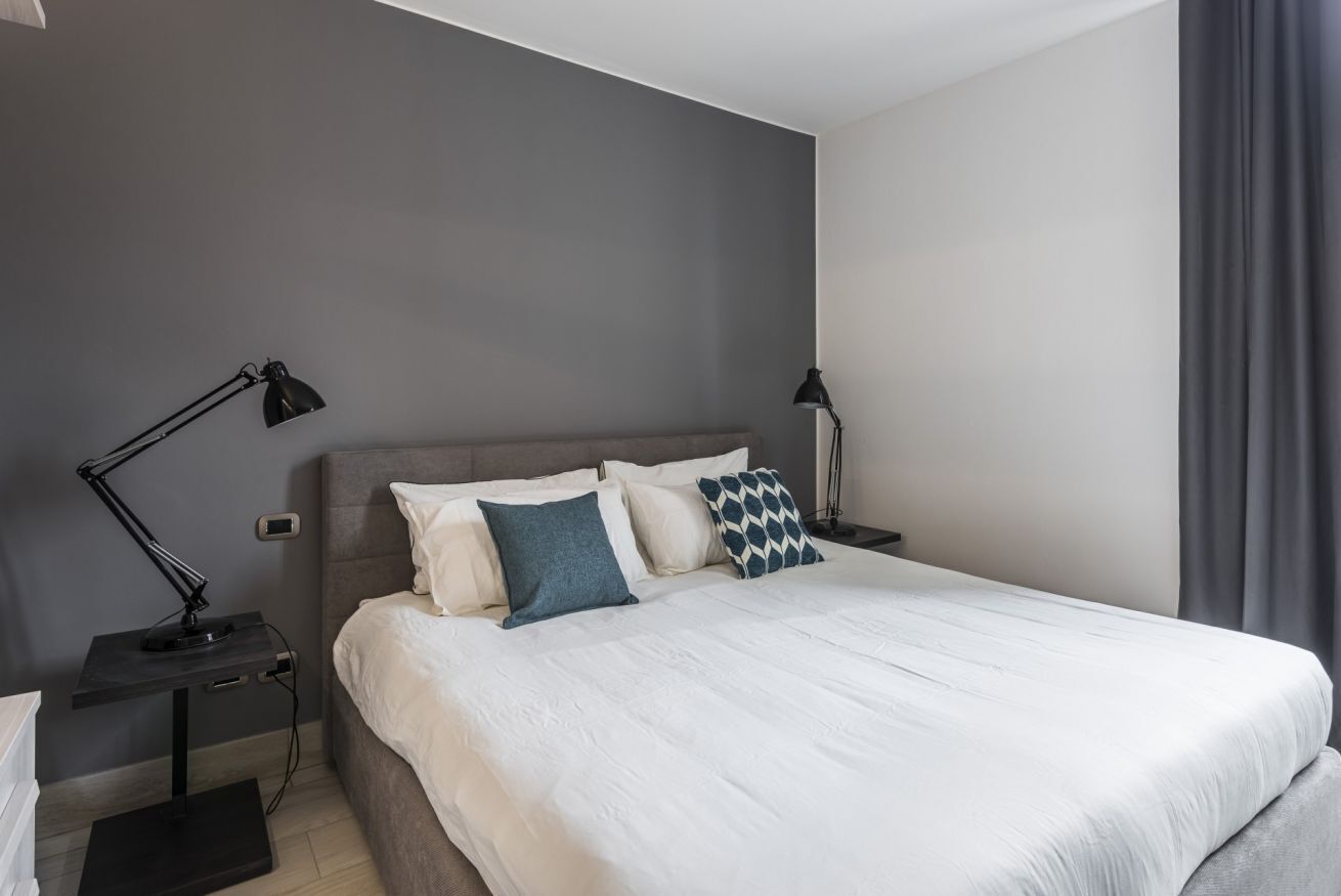 Ein modernes Schlafzimmer mit einem großen Bett, zwei Nachttischen und einem Beistelltisch.