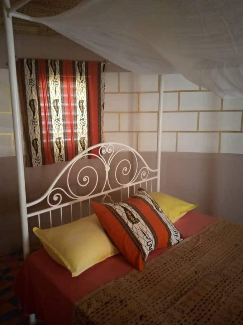 A bed with a metal headboard, red bedding, and patterned pillows.
