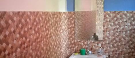 A bathroom with a patterned wall, a sink, and a mirror.