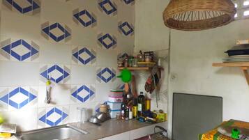 Una cocina con un salpicadero decorativo, una lámpara colgante de mimbre y una estufa.
