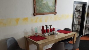 Un comedor con una mesa de madera, cuatro sillas, un mantel individual rojo, velas y una botella.