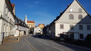 Una calle con edificios históricos, incluyendo una iglesia con campanario y un edificio con tejado triangular.