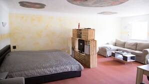 Un dormitorio con una cama, un mueble de almacenamiento de madera, un sofá y una mesa de centro.