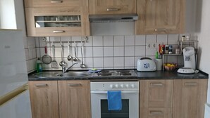 Una cocina con armarios de madera, una estufa blanca, un lavamanos y un tostador.