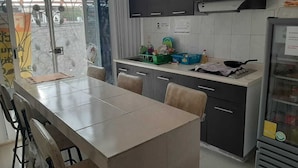 Una cocina moderna con una mesa de comedor, sillas, armarios y un refrigerador.