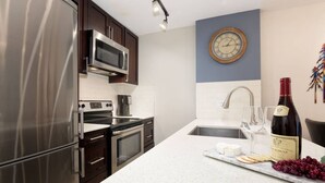 A modern kitchen with stainless steel appliances, a white countertop, and a wine bottle. - Luxury Ski-in/out 1Br/1Ba - 3Hot Tub`s & Pool (Whistler)