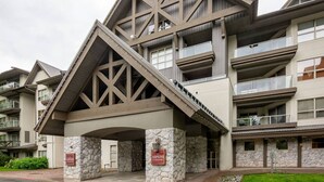 A multi-story hotel with a distinctive architectural design featuring stone pillars and a sloped roof. - Luxury Ski-in/out 1Br/1Ba - 3Hot Tub`s & Pool (Whistler)