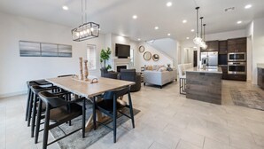 A spacious living area with a dining table, sofas, and a kitchen area with modern appliances.