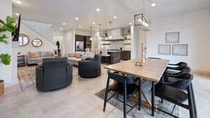 A spacious living area with a dining table, sofas, and a staircase leading to another level.