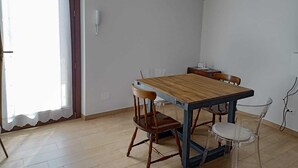 Un comedor con una mesa y sillas de madera, una pared blanca y un equipo de aire acondicionado.