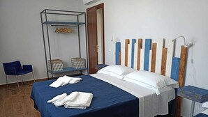 Un dormitorio con cama, una silla, un armario y una mesita de noche.