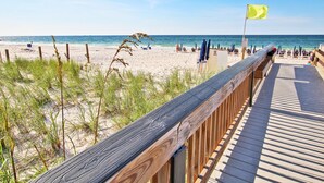 A wooden boardwalk leading to a beach with a flag. - Crystal Tower 1801 (Gulf Shores)