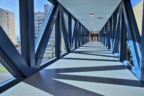 A corridor with a modern architectural design, featuring a series of triangular frames and large windows.