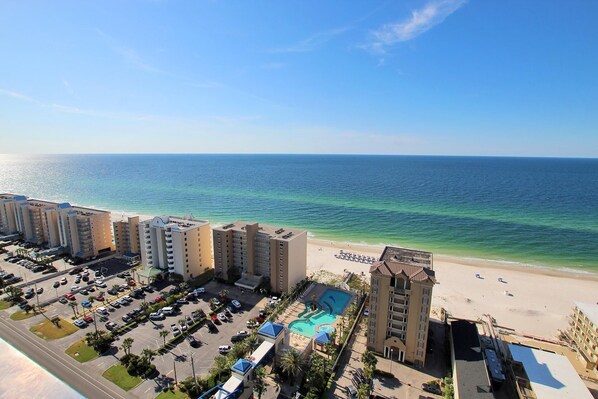 A beachfront hotel with multiple buildings, a parking lot, and a swimming pool. - Crystal Tower 1702 (Gulf Shores)